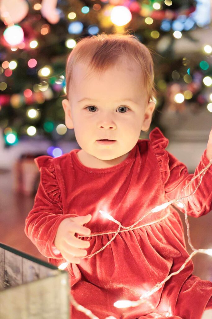 Baby looks at the camera as she plays with string lights during Main Line Baby photography session