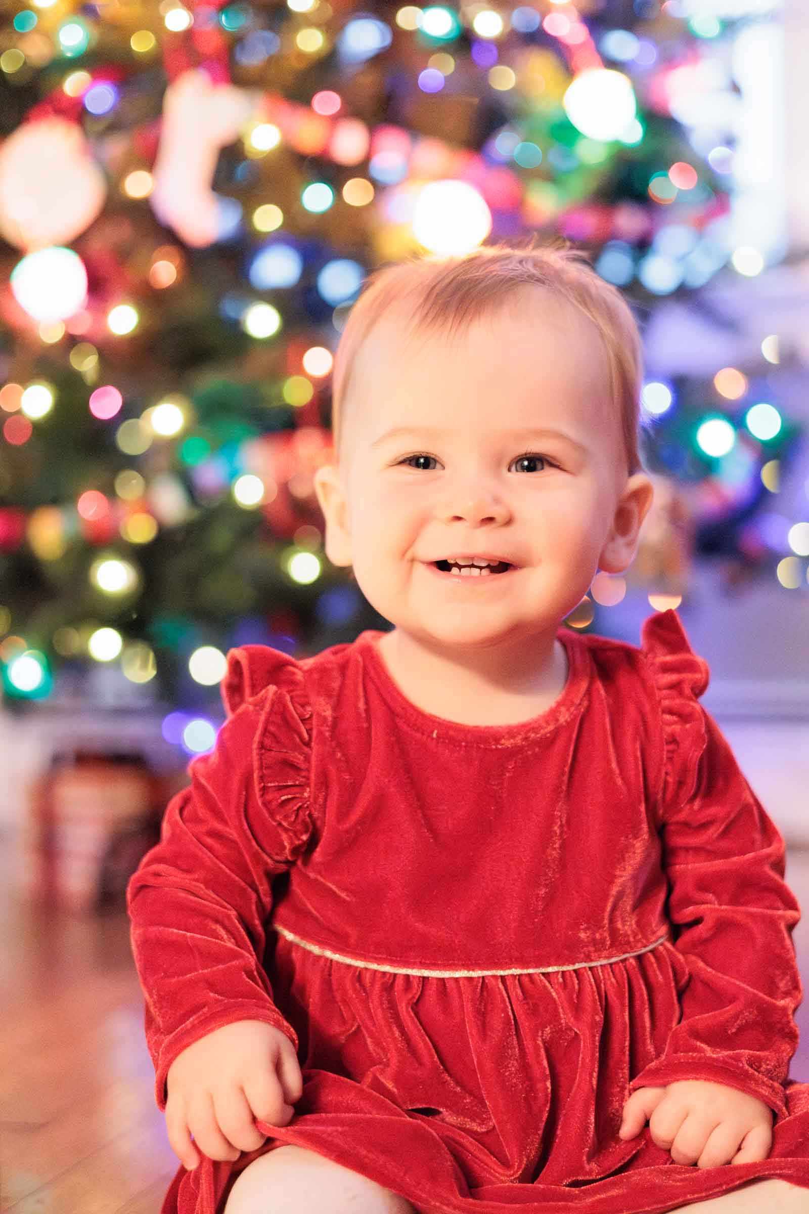 Baby smiles happily at camera during in-home family photo session.