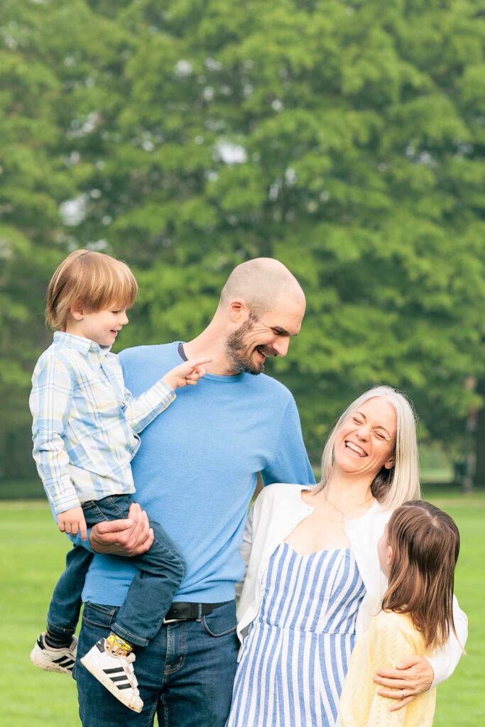 Family of four smiles and laughs while looking at one another in Haverford, PA