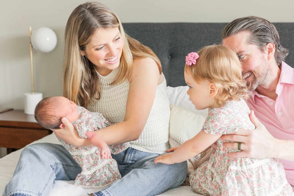 Family looks at newborn while smiling