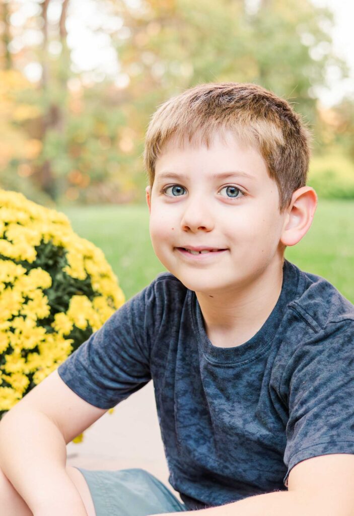 Portrait of young boy next to yellow flowers