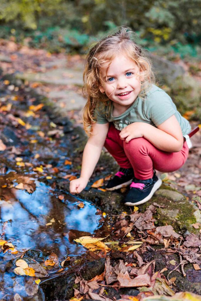 Portrait of toddler girl playing in water during mini session by Lower Merion photographer