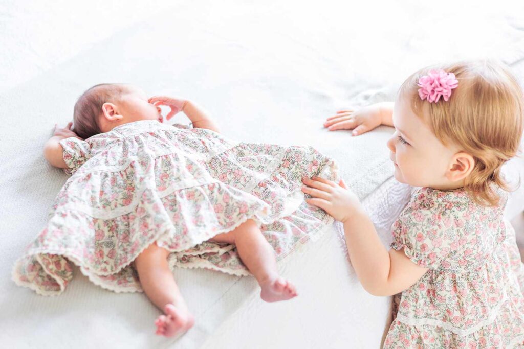 Baby looks at newborn during family photo session