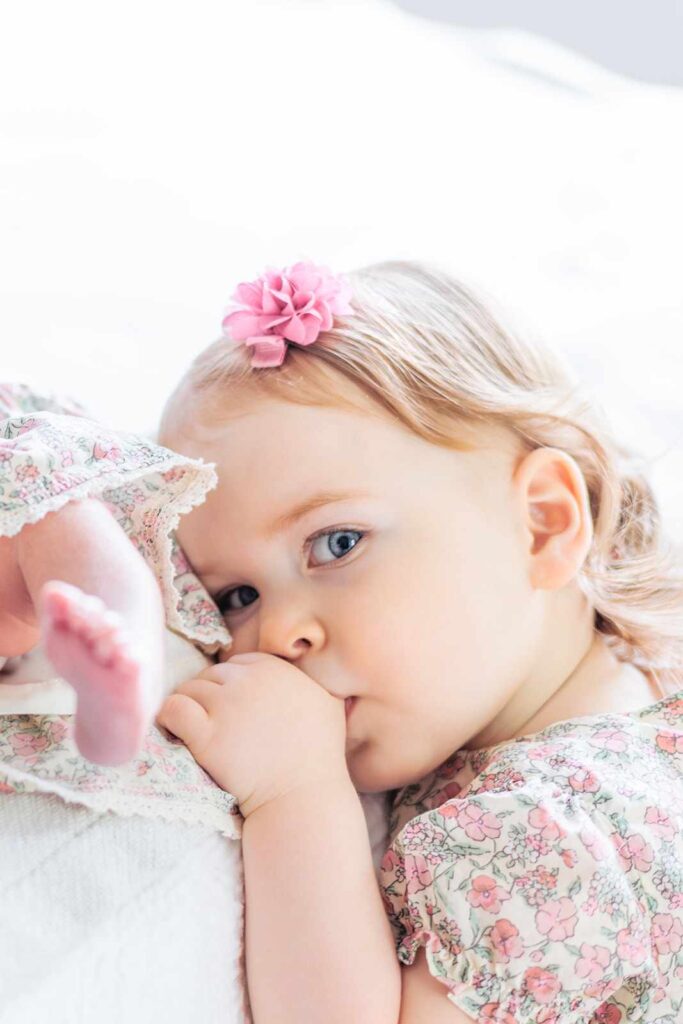 Toddler sucks her thumb and looks to camera