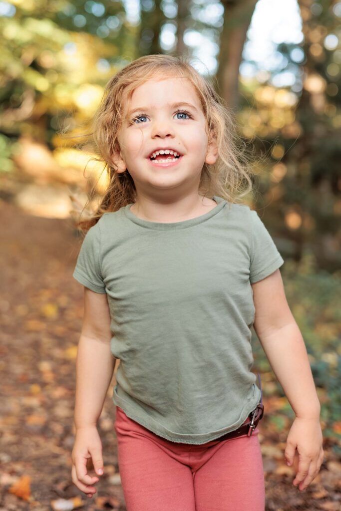 Toddler girl walks through wooded area during Main Line mini session