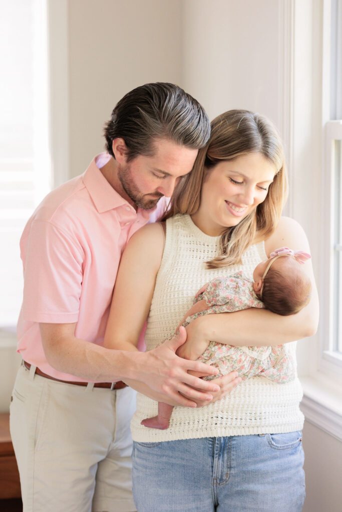 Parents look at newborn girl during in home newborn session.