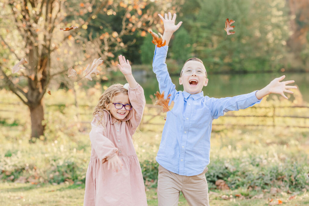 Joyful siblings play in the leaves during fall photos mini session Philadelphia Main Line