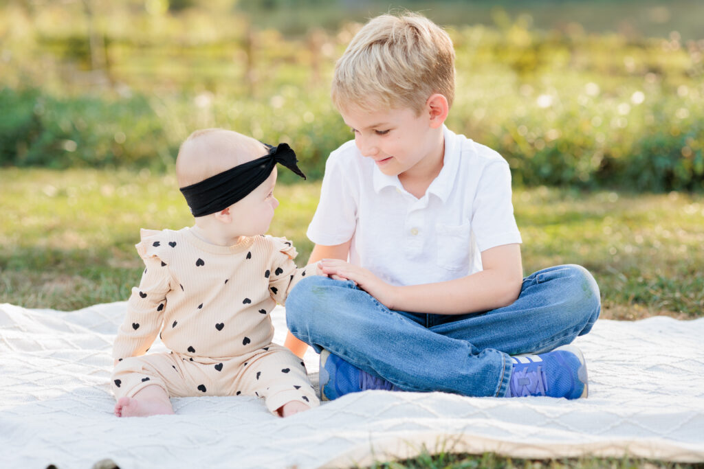 Baby looks at older brother while seated on a blanket during photo session on Philadelphia's Main Line